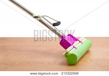 Purple plastic mop with metal tubular handle mounting clamp and green sponge on a wooden floor on a white background