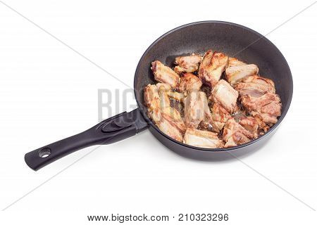 Fried pork ribs on the cast aluminium frying pan with ceramic non-stick coating on a white background