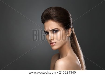 Beautiful woman with evening make-up and updo. Fashion photo. Girl ower dark background. Studio shoot.