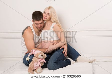 Beautiful pregnant couple in love on the background. Hands of husband on the tummy of his pregnant wife. Young man tenderly stroked pregnant belly of his wife. Husband kissing pregnant belly.