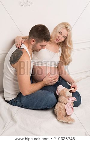 Beautiful pregnant couple in love on the background. Hands of husband on the tummy of his pregnant wife. Young man tenderly stroked pregnant belly of his wife. Husband kissing pregnant belly.