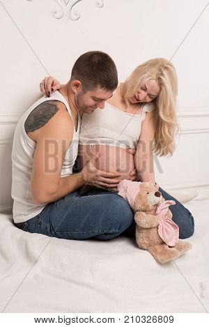 Beautiful pregnant couple in love on the background. Hands of husband on the tummy of his pregnant wife. Young man tenderly stroked pregnant belly of his wife. Husband kissing pregnant belly.