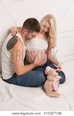Beautiful pregnant couple in love on the background. Hands of husband on the tummy of his pregnant wife. Young man tenderly stroked pregnant belly of his wife. Husband kissing pregnant belly.