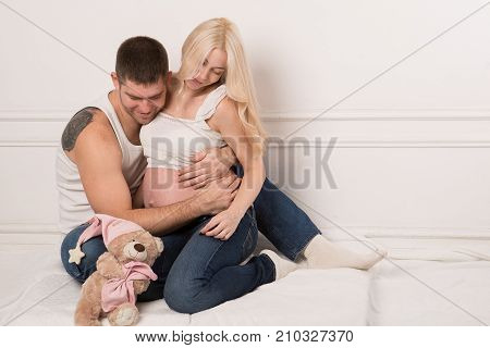 Beautiful pregnant couple in love on the background. Hands of husband on the tummy of his pregnant wife. Young man tenderly stroked pregnant belly of his wife. Husband kissing pregnant belly.
