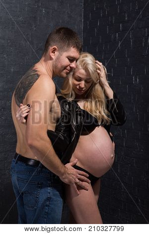 Beautiful pregnant couple in love on the background. Hands of husband on the tummy of his pregnant wife. Young man tenderly stroked pregnant belly of his wife. Husband kissing pregnant belly.