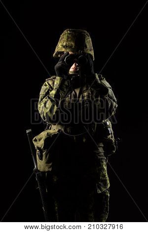 Portrait of armed woman with camouflage. Young female soldier observe with binoculars. Child soldier with gun in war black background. Military army people concept