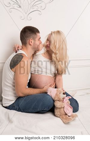 Beautiful pregnant couple in love on the background. Hands of husband on the tummy of his pregnant wife. Young man tenderly stroked pregnant belly of his wife. Husband kissing pregnant belly.