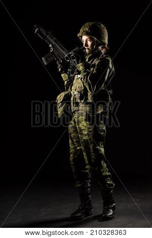 Portrait of armed woman with camouflage. Young female soldier observe with binoculars. Child soldier with gun in war black background. Military army people concept