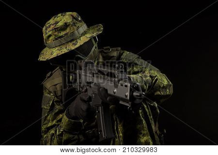 Portrait of armed woman with camouflage. Young female airsoft sniper observe with firearm. Soldier with gun in war black background. Military army people concept