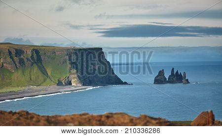 Amazing black arch of lava standing in the sea on small peninsula. Popular tourist attraction. insane basalt columns, lava formations, towering cliffs, and caves. Reynisfjara Black Sand Beach is a must-see in Iceland