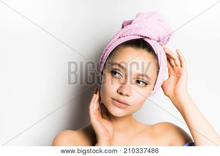 lovely girl after a shower with a pink towel on her head mysteriously looks aside. beautiful woman