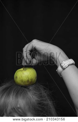 Woman holding a green apple on a top of her head selective color vertical shot