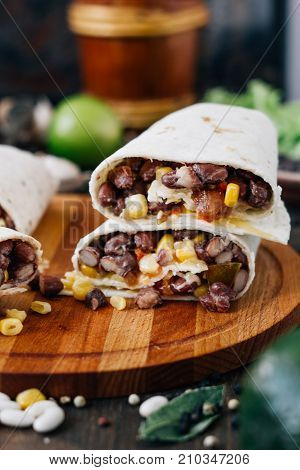Nice vegetarian burrito over black table on wooden board