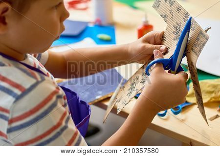 Portrait of cute little boy  cutting paper in arts and crafts class of pre-school making handmade gift
