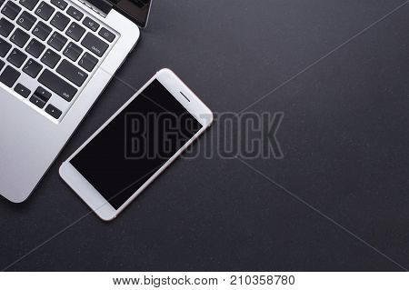 Modern Smartphone And Laptop On Black Stone Table Board. Top View With Free Space For Text Or Design