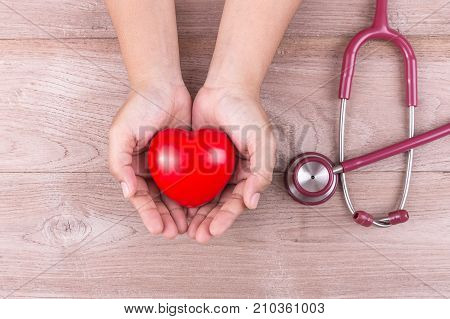 Check Heart Concept : Woman Hands Holding Red Heart And Stethoscope On Brown Wooden Table