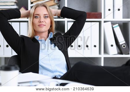 Business woman resting in the office after a working day throwing her feet on the table leaning back her hands behind her head