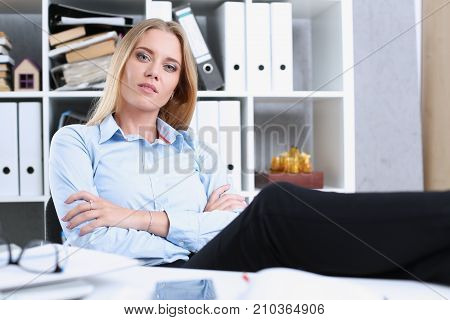 Business woman resting in the office after a working day throwing her feet on the table leaning back her hands behind her head