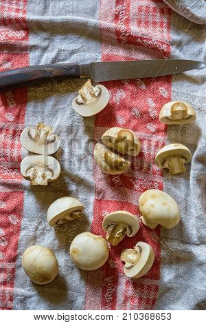 Close up fresh mushrooms cut in halves and old knife lying on cloth for abstract background