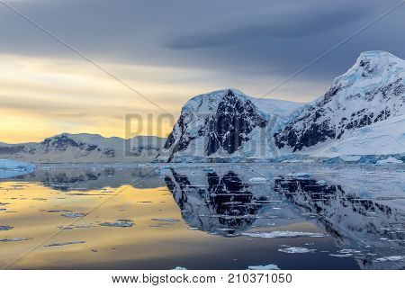 Cold Still Water Of Antarctic Lagoon With Glaciers And Mountains In The Background, Antarctica