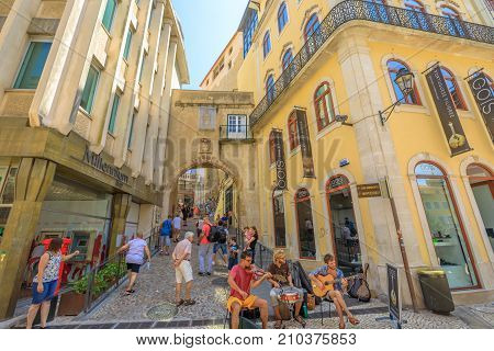 Coimbra, Portugal - August 14, 2017: people walk through Tower and Arch of Almedina, the iconic Archway of Almedina, fortification of Manuelino period in historic medieval Coimbra, Central Portugal.