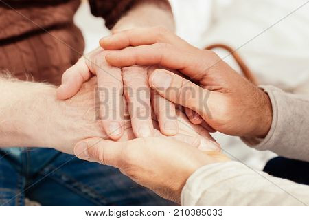 Love you. Loving grandson vising his granddaddy and embracing his hands while feeling happiness