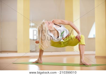 Beautiful sporty fit yogi woman practices yoga asana Parivritta Stupasana in the yoga class