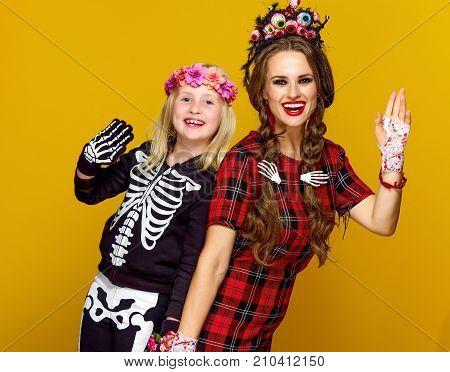 Smiling Modern Mother And Child In Halloween Costume Handwaving