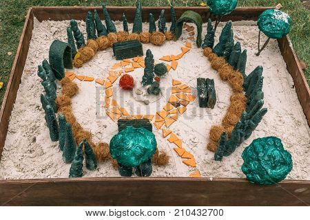 Miniature houses, toy landscape objects in sandbox. Anti-stress and soothing sand therapy. Landscape Layout