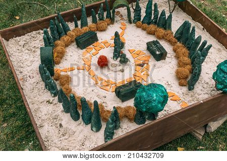 Miniature houses, toy landscape objects in sandbox. Anti-stress and soothing sand therapy. Landscape Layout