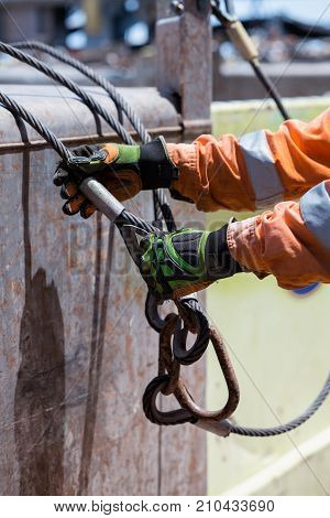Able seaman is connecting sling. Crane loading operations on deck of offshore  platform supply PSV vessel.  Hes is wearing safety gloves and coverall.