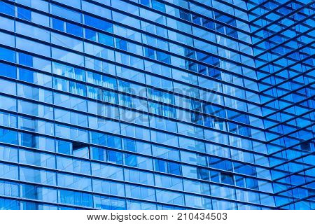 Abstract shot of glass transparent skyscraper office building for texture or background. Blue toned