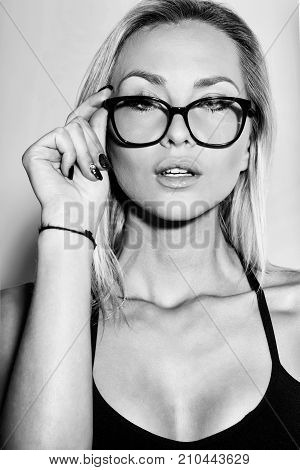 Pretty secretary girl or businesswoman in cute stylish black eyeglasses with long blond hair on grey background. business and office concept