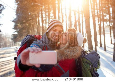 Selfie of love couple in sunny forest on winter