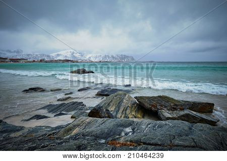 Waves of Norwegian sea on rocky beach of fjord. Ramberg beach, Lofoten islands, Norway