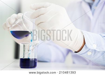 scientists and scientific equipment Pouring mixing reagents liqiud beakerLaboratory research chemistry concept