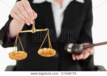Jeune femme tenant des balances de la Justice et un marteau avec l'objectif de la caméra sur les échelles