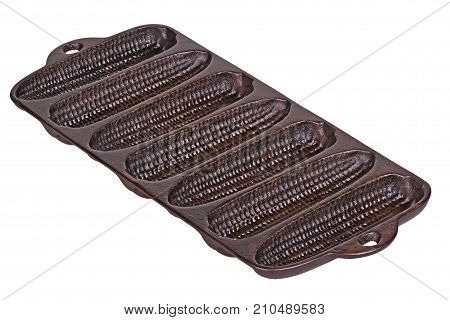Old but seasoned cast-iron pan ready for baking cornbread sticks in the shape of corn on the cob isolated against a white background