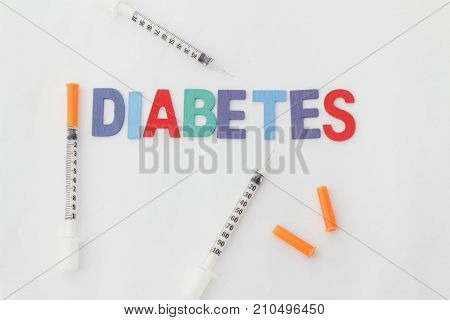 Word DIABETES and insulin syringes on isolated white background