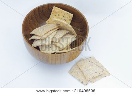 Whole grain crackers / crispy bread inside a wooden bowl on isolated white background