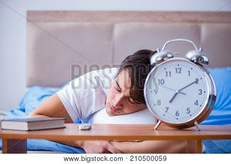 Man in bed frustrated suffering from insomnia with an alarm cloc