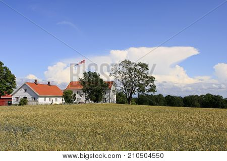 VESTFOLD, NORWAY ON JULY 08. View of a farm in sunshine, fields and crop this side on July 08, 2009 in Vestfold, Norway. Shower in the background. Editorial use.