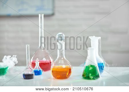 Workplace of a chemist. Table full of flasks and test tubes with colorful chemicals development equipment research survey science scientific ducation biology medicine concept.