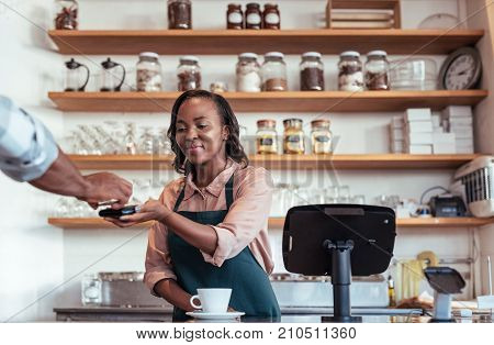 Customer paying a barista for a purchase in a cafe using a bank card and nfs technology