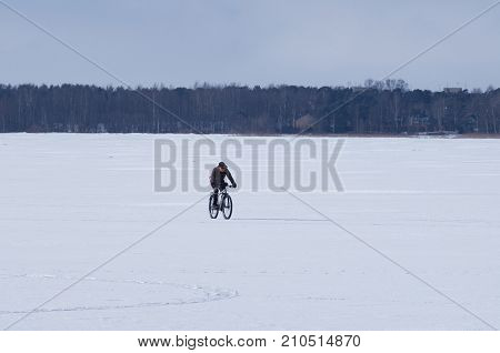 The lake Sestroretsky Razliv St.Petersburg (Russia) - March 14 2017: Male cyclist riding a bicycle in the winter barren landscape