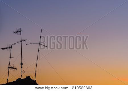 A silhouette of an old antenna against sunset sky in background