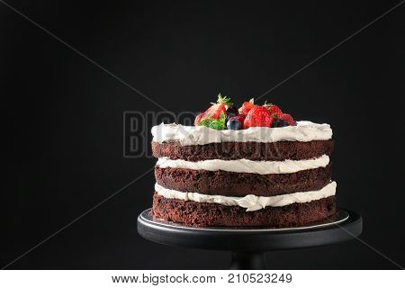 Dessert stand with delicious chocolate cake on black background