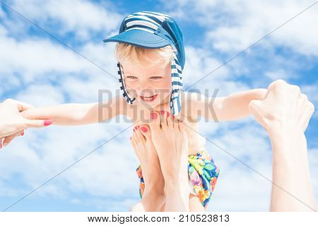 Happy momentMother throws up her smiling baby boy in the blue skysummer time