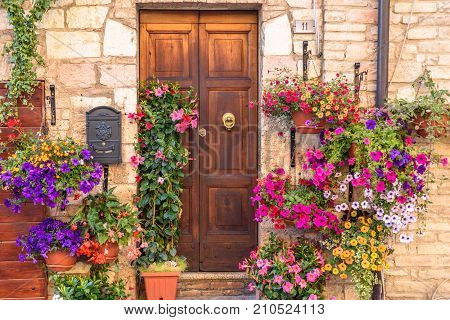 SPELLO, ITALY - MAY 27 2017 - Close up of a door of a residential building in Spello decorated with colorful flowers.