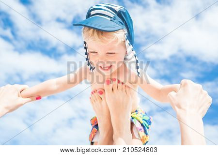 Happy momentMother throws up her smiling baby boy in the blue skysummer time